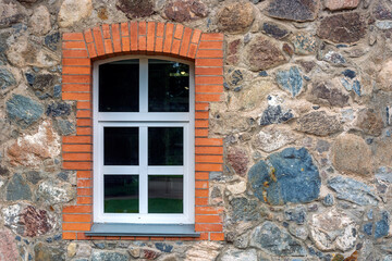 Window with a white frame framed by red brick on a stone wall. From the Window of the World series.