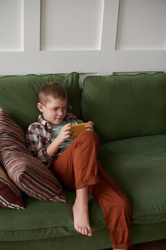 Young boy sitting and watching clips on his phone.