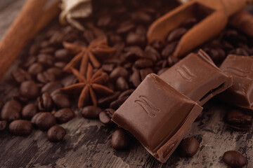 chocolate, cinnamon sticks  and coffee beans on wooden background