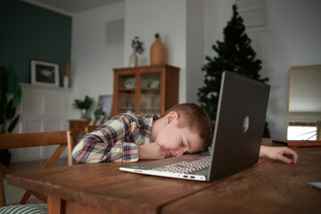 Boy Student Tired in front of Laptop Computer at Home.