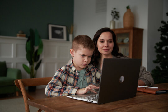 Mother helping teen boy doing homework.