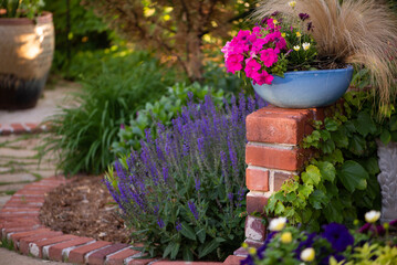 Turquoise Pot with Pink Flowers on Brick Wall in garden