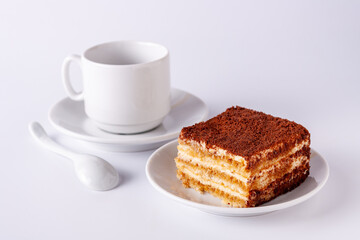 a slice of tiramisu lies on a white plate on a white background