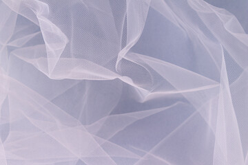 sheer tulle fabric arranged in soft folds on a blue background, selective focus - obrazy, fototapety, plakaty
