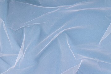 sheer tulle fabric arranged in soft folds on a blue background, selective focus