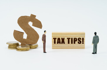 On a white surface, a dollar symbol, a figurine of businessmen and a wooden sign with the...