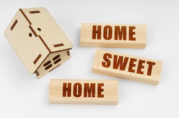 On a white surface, a wooden toy house and blocks with the inscription - Home For Sale