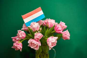 Bouquet of tulips and the flag of the Netherlands on a green background.
