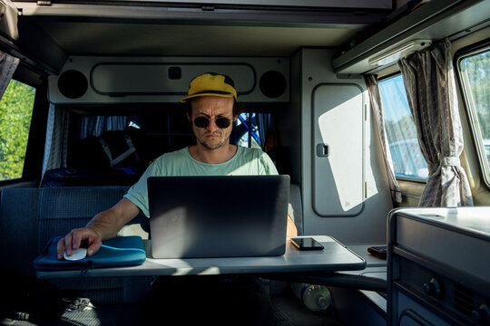 A lonely traveler guy working remotely from his camper van on the road 