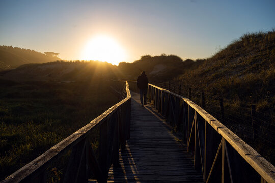 A lonely guy walking down a landing bridge on beach
