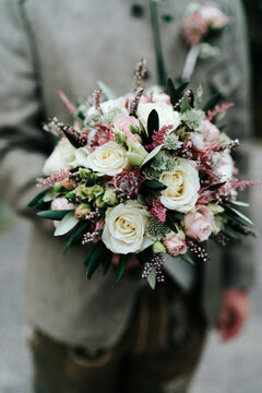 Person holding a bridal bouquet with fresh white roses