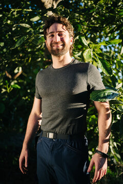 Smiling male farmer standing near tree in garden