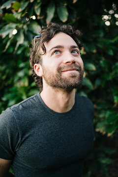 Smiling male gardener looking up near tree
