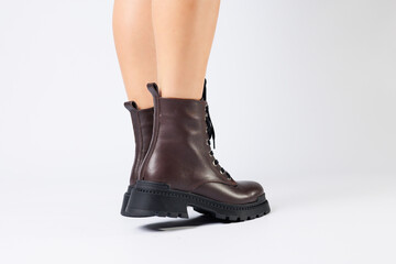 Women's brown spring boots made of genuine leather on a woman's leg. New collection of women's boots 2022