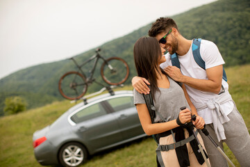Naklejka premium Couple of hikers with backpacks starting a walk through the fields