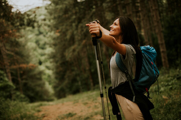 Young female backpacker woman enjoying green beautiful forest around her