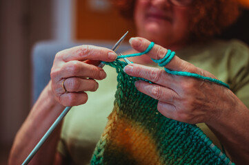 Close up of the hands of a senior woman knitting at home.