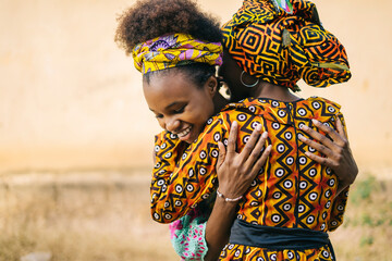Cheerful African girls hugging on street