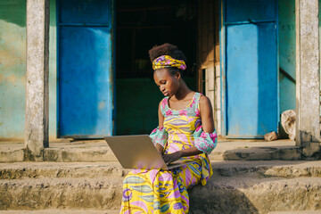 African woman browsing laptop in village