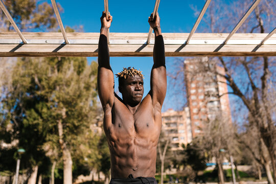 Muscular African man exercising on calisthenics bars