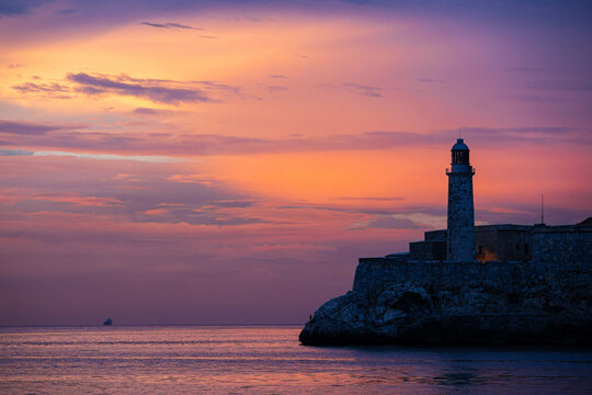 a lighthouse at sunset by the sea