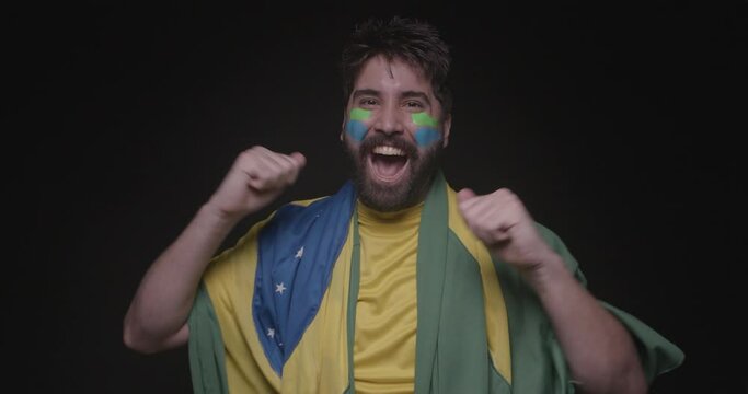 handsome man with brazilian beard, soccer fan, dancing, partying and moving body, enjoying. with clothes and flag of brazil, world cup, olympics.