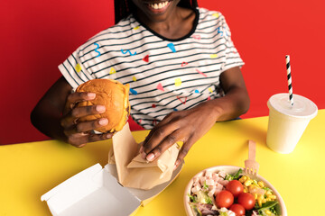 Smiling woman eating burger in studio