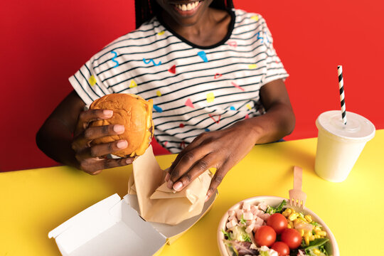 Smiling woman eating burger in studio