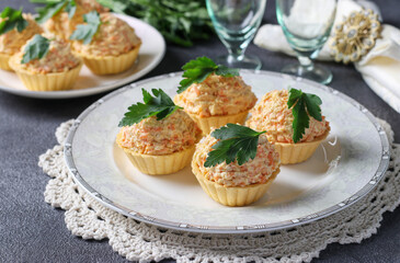 Tartlets with cheese, chicken and carrots garnished with parsley on dark gray background