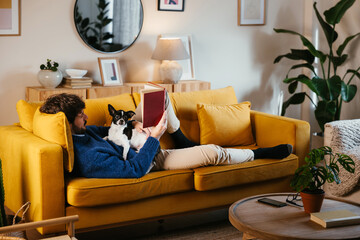 Man with dog reading book on sofa