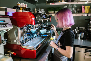Young woman using red coffee machine in cafe