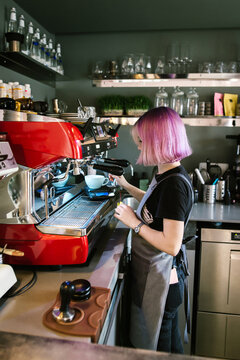 Young female bartender with pink hair working in cafe