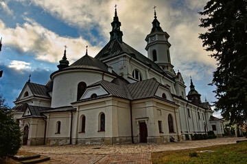 Kolegiata pod wezwaniem świętego Michała Archanioła w Ostrowcu Świętokrzyskim na tle błękitnego nieba i chmur .