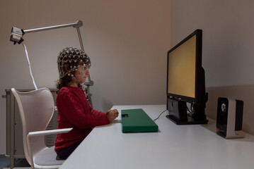 Child in EEG cap looking at monitor in laboratory