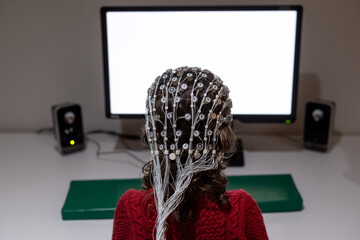 Child in EEG cap looking at monitor in laboratory