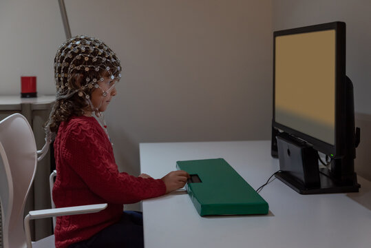 Pupil in EEG cap looking at monitor in laboratory