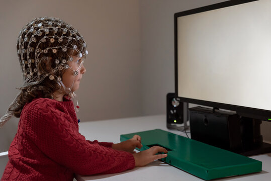 Kid in EEG cap looking at monitor in laboratory