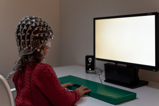 Kid in EEG cap looking at monitor in laboratory