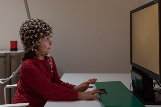 Kid in EEG cap looking at monitor in laboratory