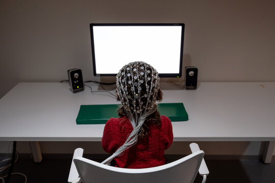 Kid in EEG cap looking at monitor in laboratory