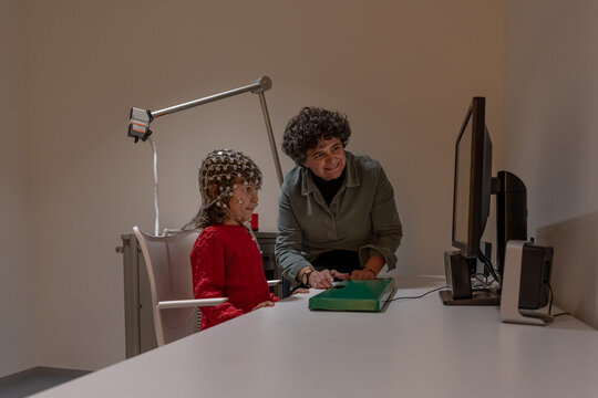 Researcher making neural study on kid in EEG cap