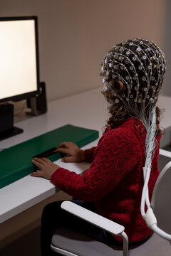 Child in EEG cap looking at monitor in laboratory