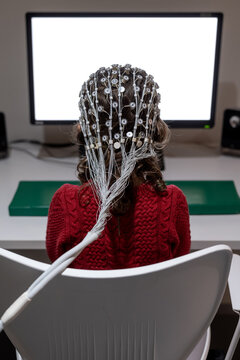 Little girl in EEG cap looking at monitor in laboratory