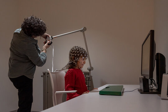 Researcher making neural study on kid in EEG cap