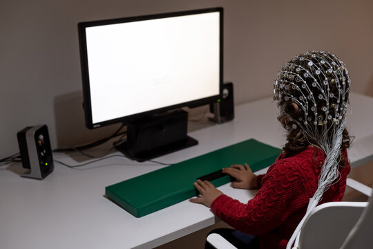 Pupil in EEG cap looking at monitor in laboratory
