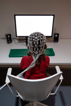Girl in EEG cap looking at monitor in laboratory