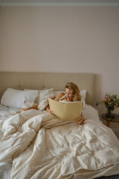 a woman reading a magazine in bed