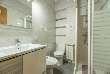 Bathroom with porcelain sink on wooden cabinet, square white aluminum shower tray and suspended aluminum radiator