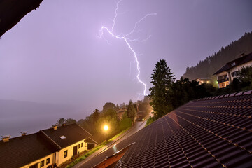 Strong lightning strike at night in the mountains of Austria during a heavy thunderstorm.