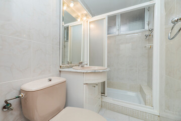Toilet with pink sanitary ware, wash basin on white marble countertop and shower cabin with white aluminum screen